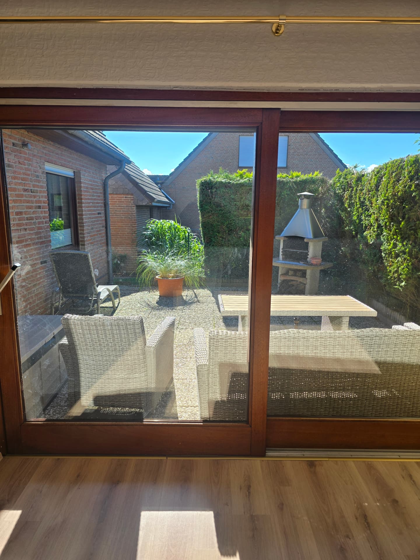 Blick durch die Terrassentür auf die Gartenterrasse mit Grill