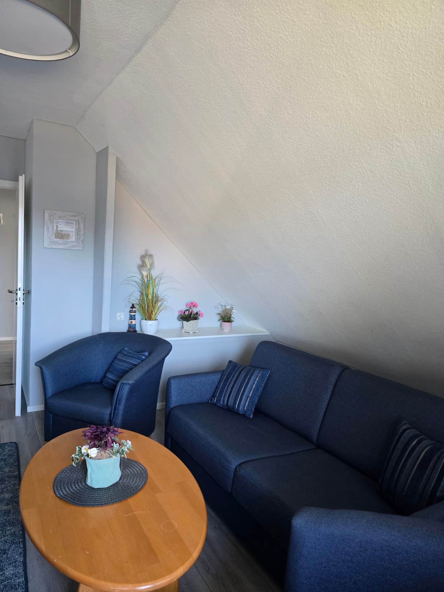 Sitzecke mit Couch, Sessel, Leuchtturm-Deko und Blumen im See Adler