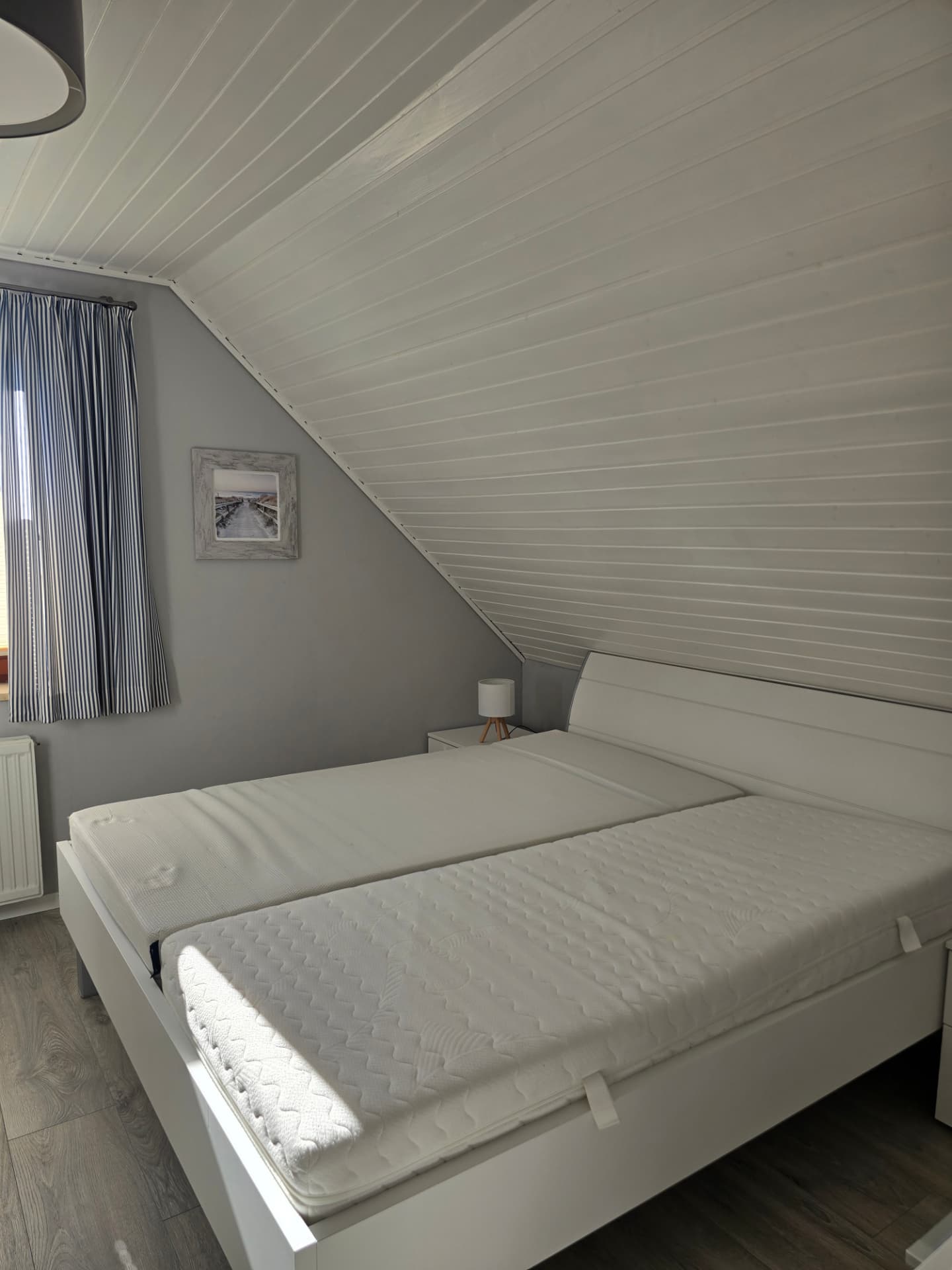 Weißes Doppelbett mit Nachttisch und Lampe im Schlafzimmer des See Adler