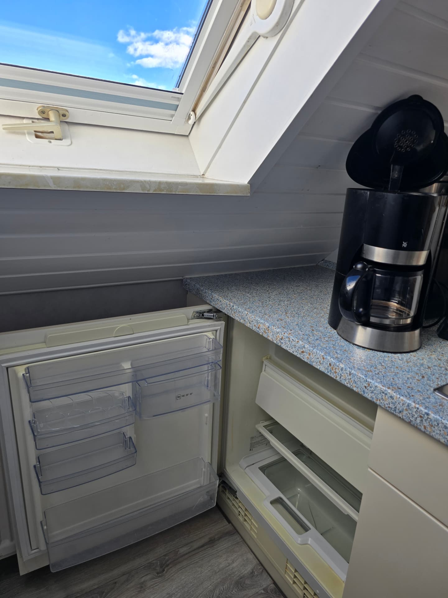 Kühlschrank mit Gefrierfach unter der Dachschräge neben der Kaffeemaschine