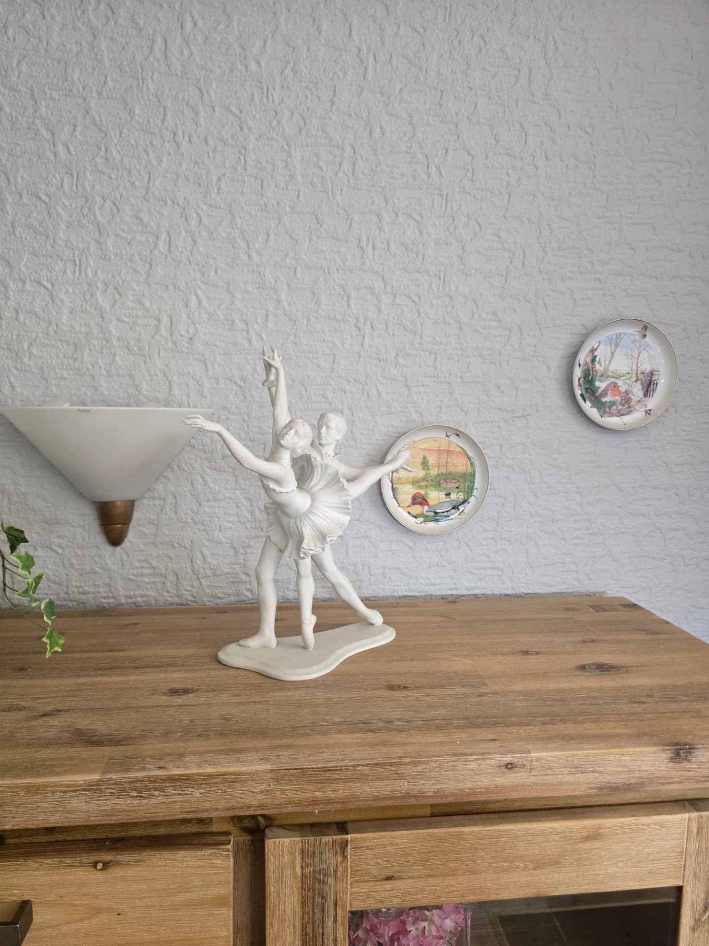 Porzellanfigur tanzender Ballerinen auf der Holzkommode mit Wandtellern