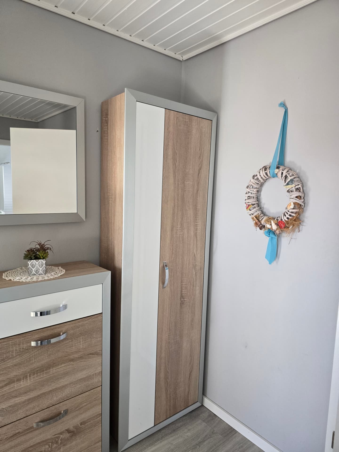 Schlafzimmerecke mit Kleiderschrank, Kommode und maritimem Türkranz im See Adler