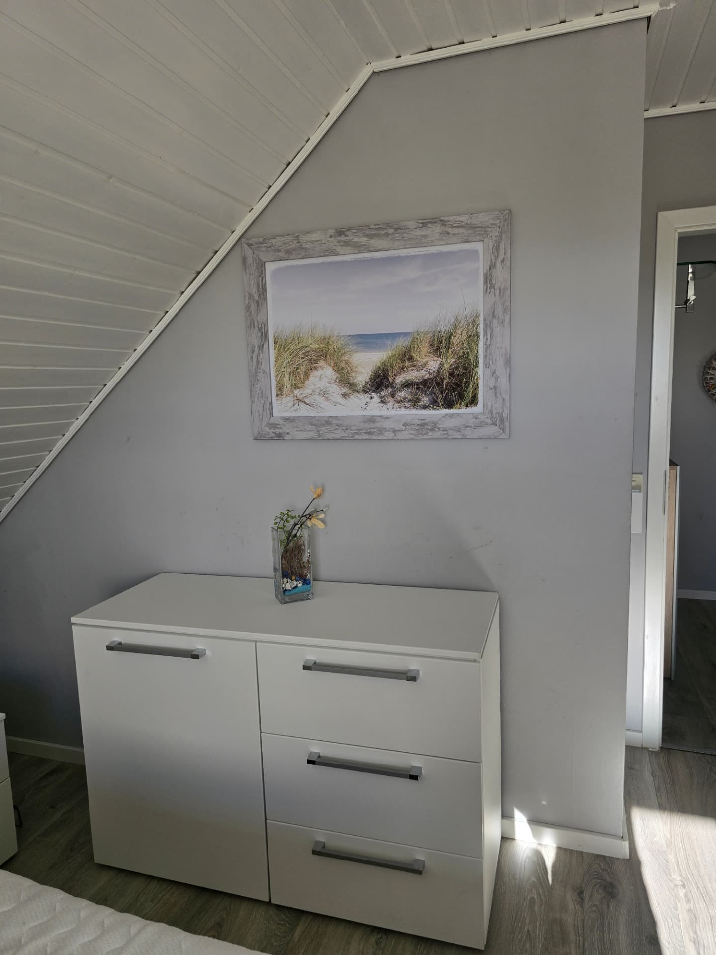 Schlafzimmer-Ecke unter der Dachschräge mit Kommode, Strandbild und Dachschrägen-Verkleidung