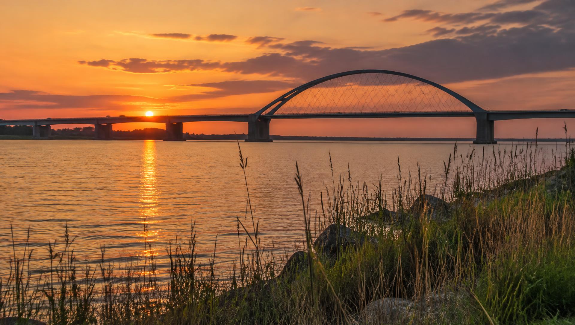 Die Fehmarnsundbrücke als Silhouette im Sonnenuntergang über dem Fehmarnsund