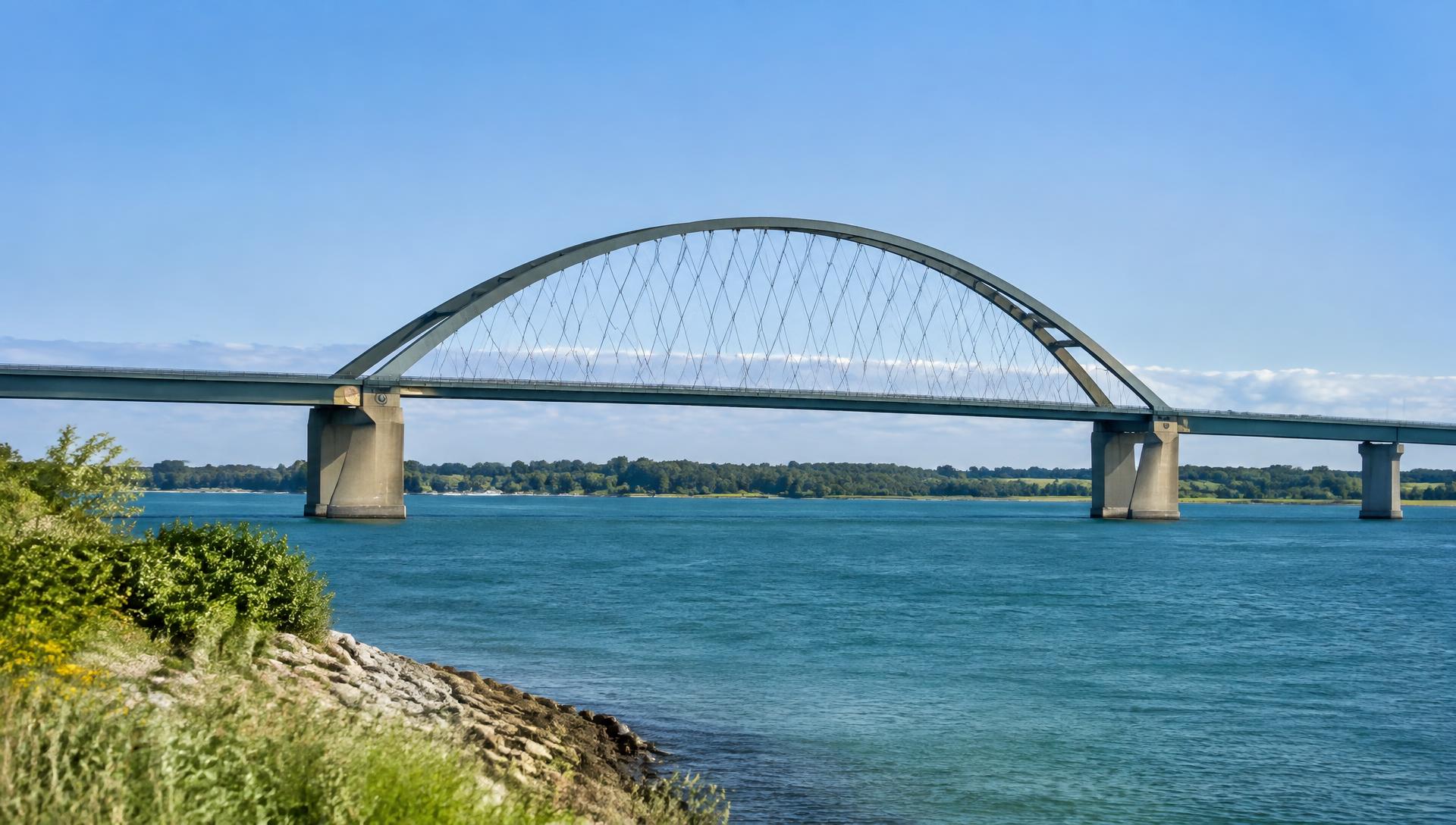 Die Fehmarnsundbrücke mit Stahlbogen über dem blauen Fehmarnsund