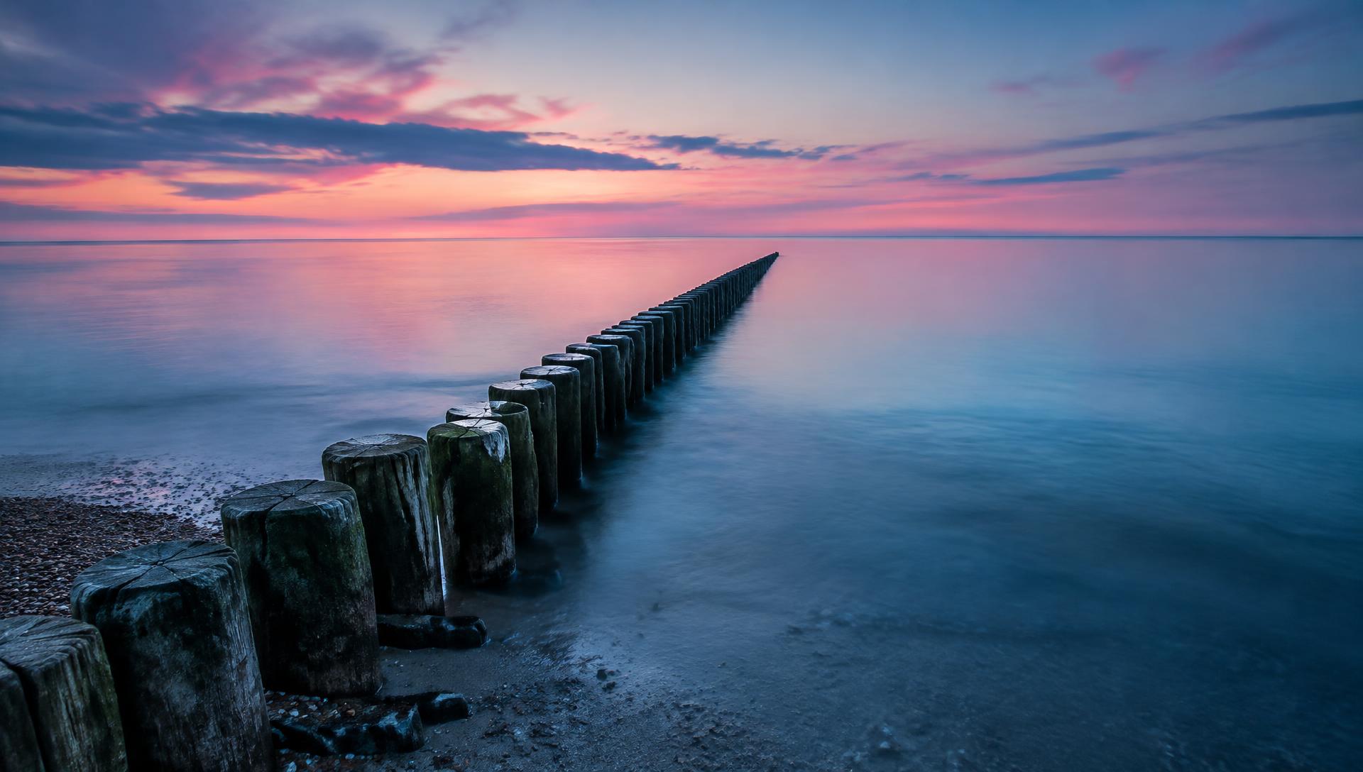 Holzbuhnen in der spiegelglatten Ostsee bei rosa Abendhimmel