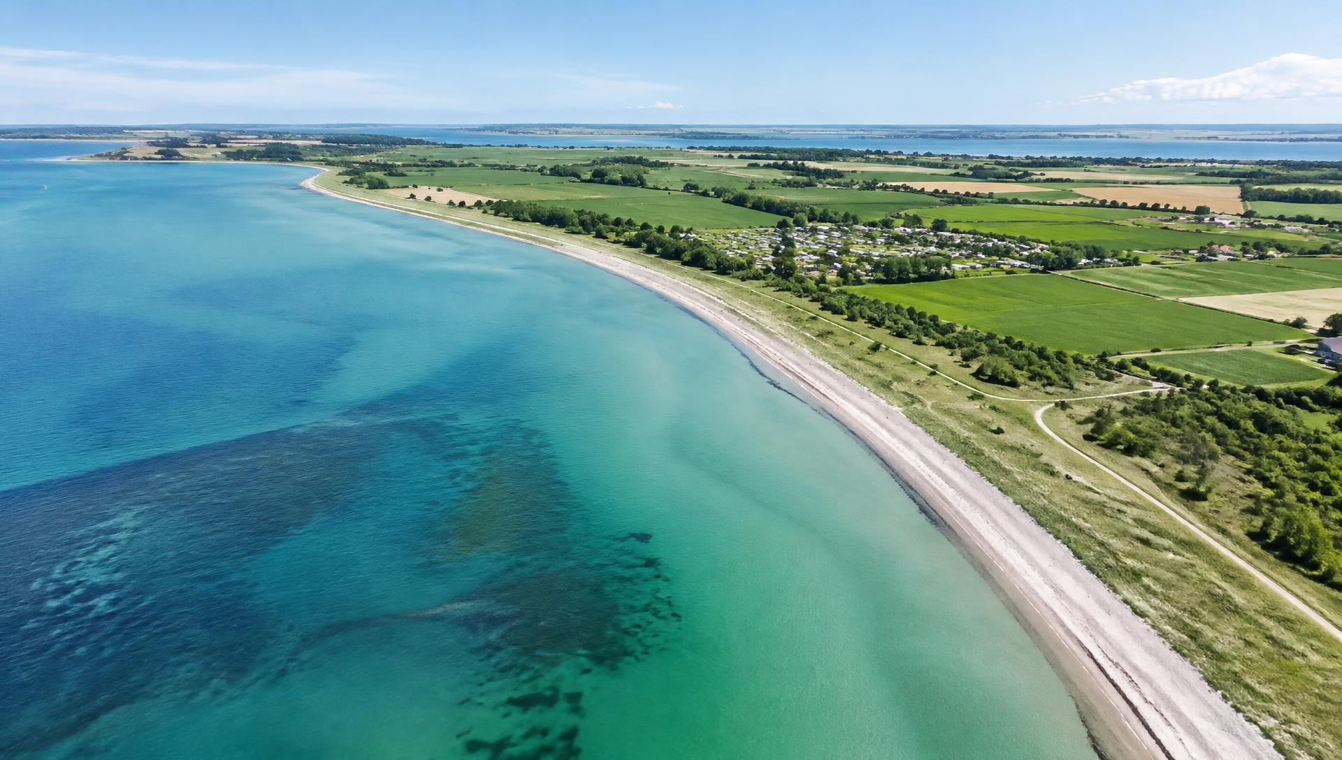 Luftbild der Küste mit türkisfarbenem Wasser, Strand und Feldern