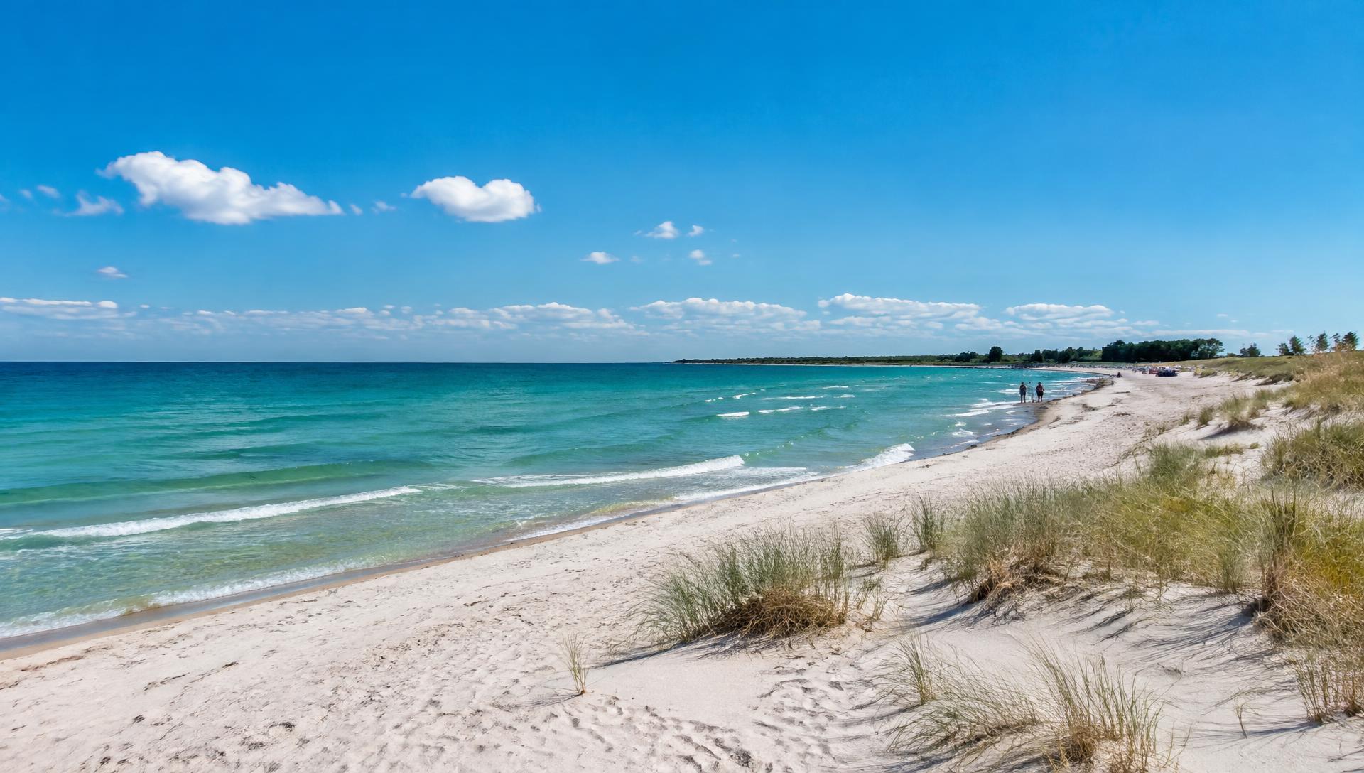 Weißer Sandstrand mit türkisfarbener Ostsee und Dünengras